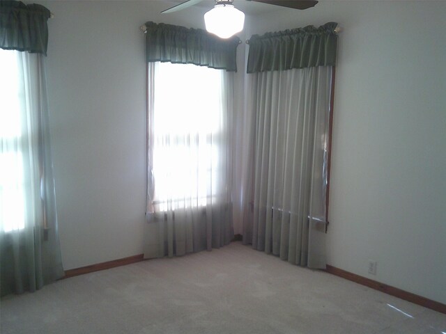 carpeted spare room featuring ceiling fan