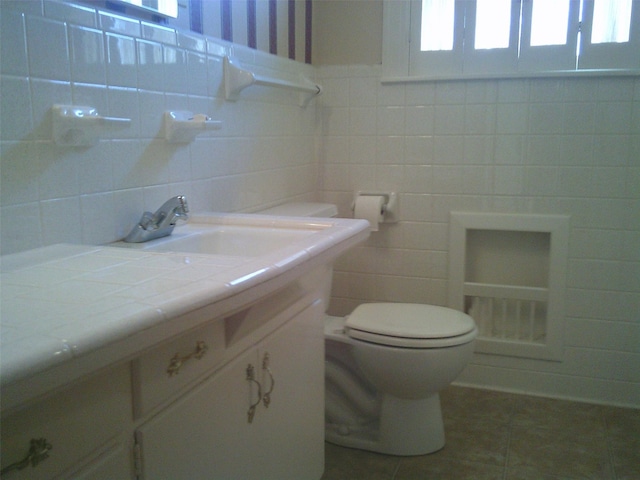 bathroom with tile patterned floors, vanity, toilet, and tile walls