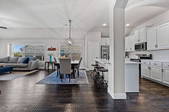 kitchen with white cabinetry, a kitchen bar, decorative light fixtures, and appliances with stainless steel finishes