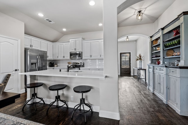 kitchen with appliances with stainless steel finishes, a kitchen breakfast bar, sink, and white cabinets