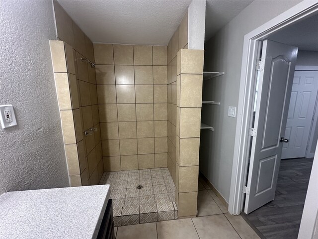 bathroom with tile patterned flooring, tiled shower, and a textured ceiling