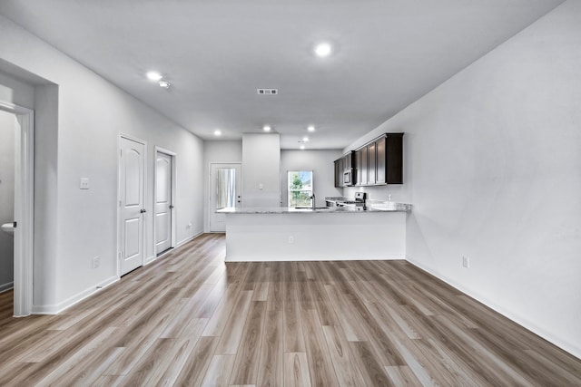 kitchen featuring sink, light hardwood / wood-style flooring, range, dark brown cabinetry, and kitchen peninsula