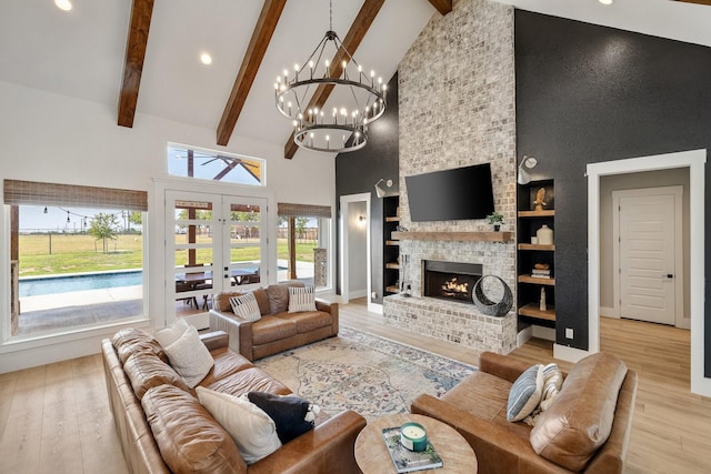 living room featuring built in shelves, a fireplace, high vaulted ceiling, and french doors