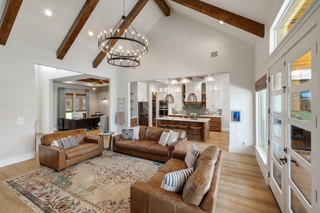 living room with light hardwood / wood-style flooring, high vaulted ceiling, and a notable chandelier