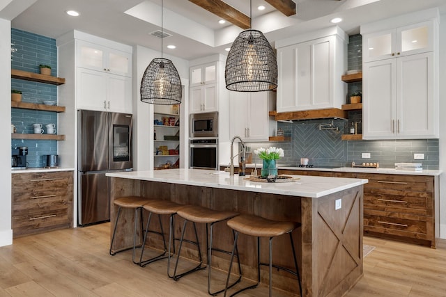 kitchen featuring light stone countertops, white cabinetry, an island with sink, and appliances with stainless steel finishes