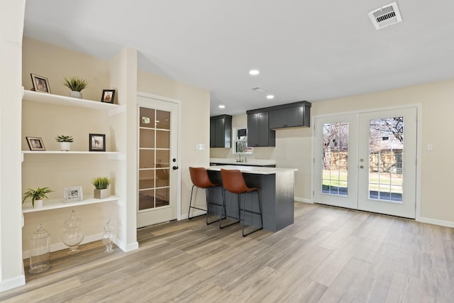 kitchen with french doors, hardwood / wood-style flooring, kitchen peninsula, and a breakfast bar