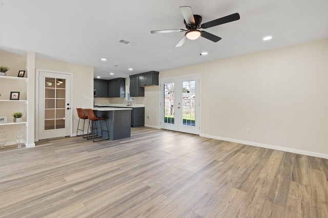 unfurnished living room with ceiling fan, french doors, and light hardwood / wood-style flooring