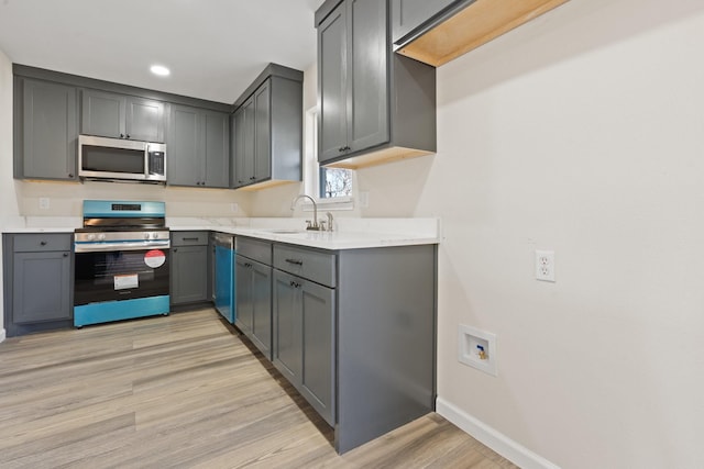 kitchen with stainless steel appliances, sink, light hardwood / wood-style floors, and gray cabinets