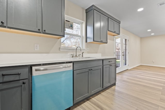 kitchen featuring stainless steel dishwasher, sink, gray cabinetry, and light hardwood / wood-style flooring