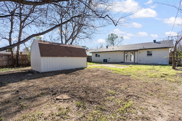 rear view of property featuring french doors, a yard, and a storage unit