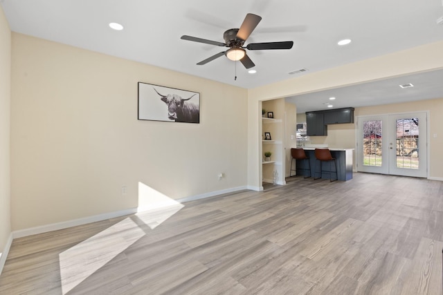 unfurnished living room featuring ceiling fan, hardwood / wood-style floors, built in features, and french doors