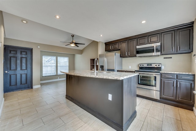 kitchen with ceiling fan, an island with sink, vaulted ceiling, and appliances with stainless steel finishes