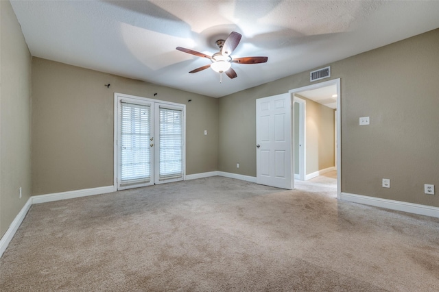 carpeted empty room with french doors, ceiling fan, and a textured ceiling