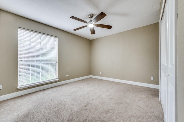 carpeted empty room featuring ceiling fan and plenty of natural light