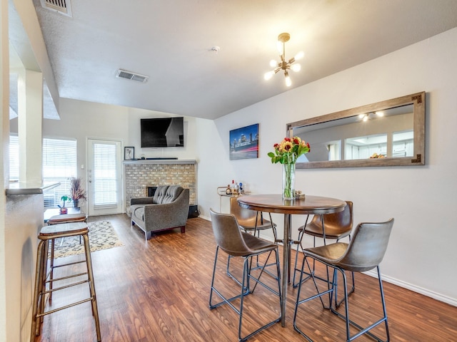 dining space with a fireplace, dark hardwood / wood-style floors, and an inviting chandelier