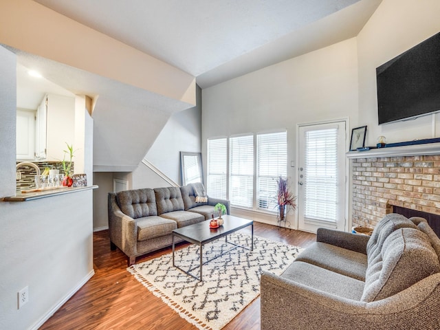 living room featuring a fireplace, wood-type flooring, and vaulted ceiling