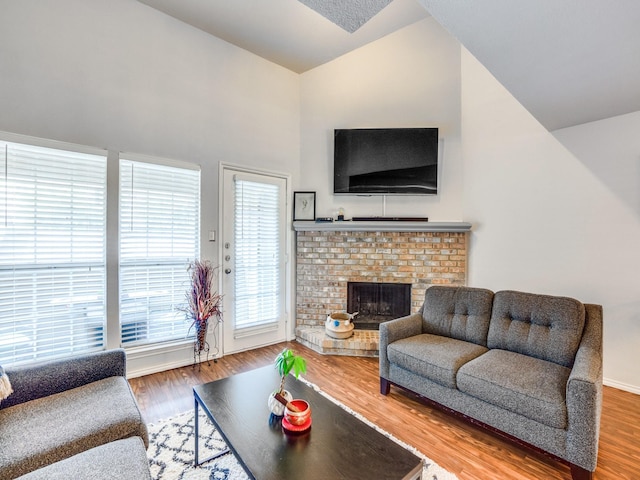 living room featuring lofted ceiling, wood-type flooring, and a fireplace