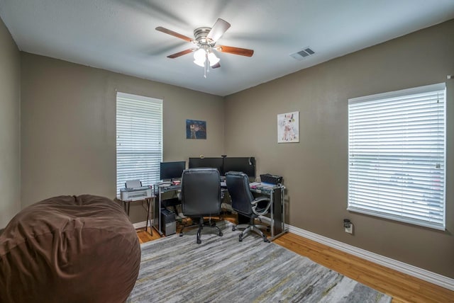 office area with light wood-type flooring, ceiling fan, and a healthy amount of sunlight