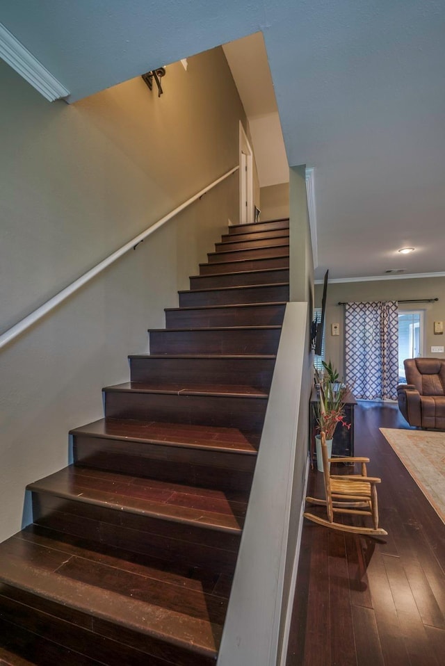 staircase featuring wood-type flooring and ornamental molding