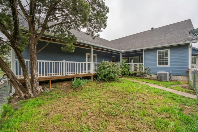 rear view of house featuring central AC unit and a yard