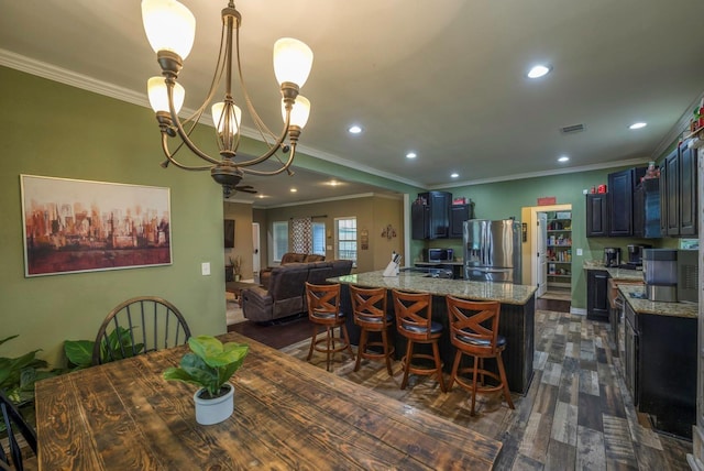 dining area featuring dark hardwood / wood-style flooring, an inviting chandelier, and crown molding