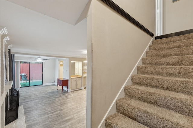 stairs featuring hardwood / wood-style floors and ceiling fan