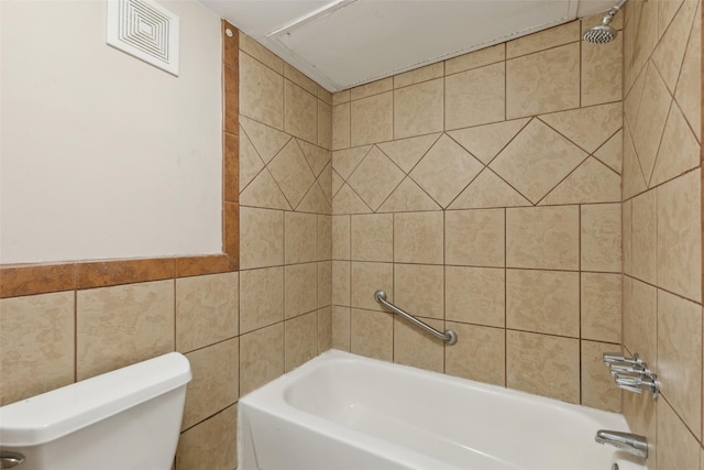 bathroom featuring tiled shower / bath combo, tile walls, and toilet