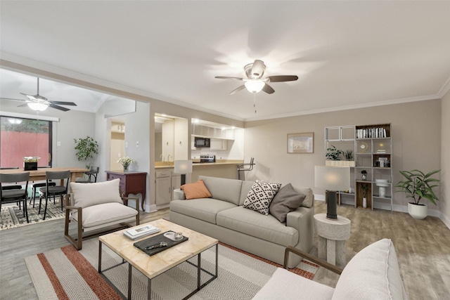 living room with ceiling fan, ornamental molding, and light hardwood / wood-style flooring