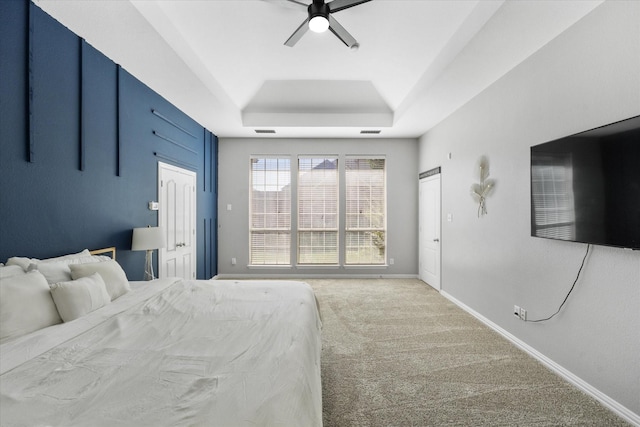 carpeted bedroom featuring ceiling fan and a raised ceiling