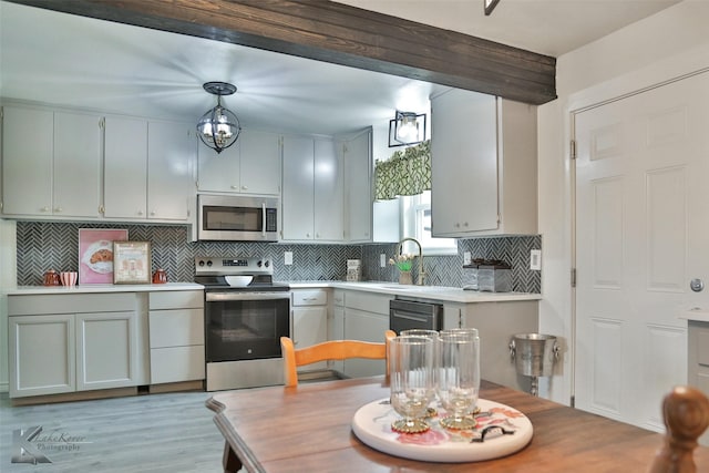 kitchen featuring decorative backsplash, stainless steel appliances, sink, beamed ceiling, and hanging light fixtures