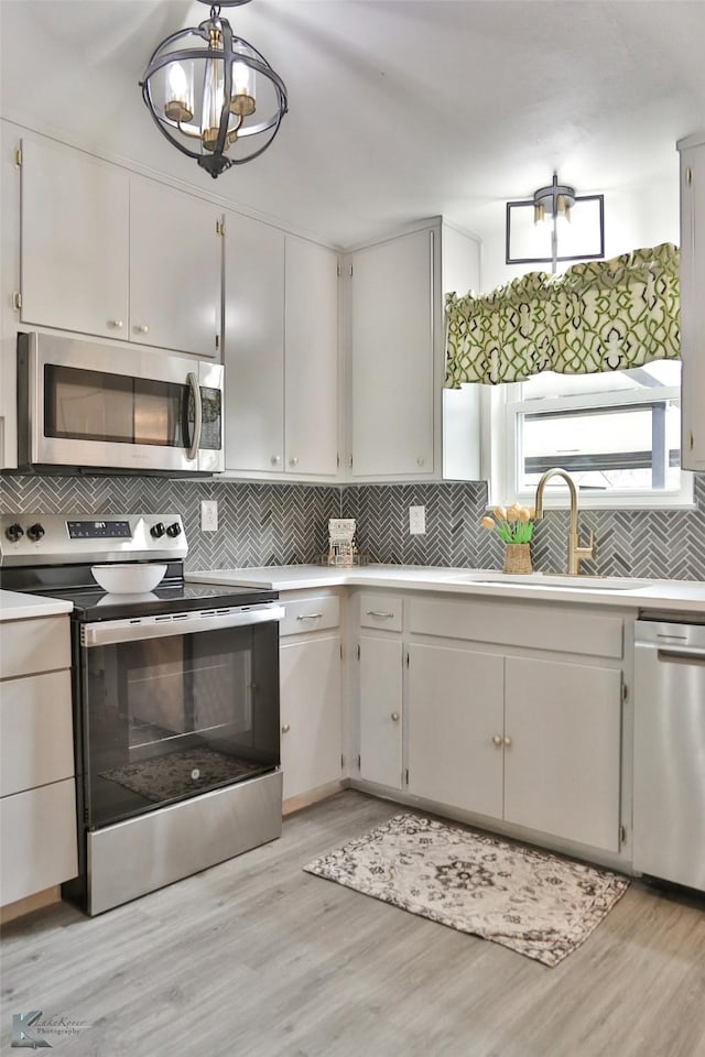 kitchen with white cabinets, appliances with stainless steel finishes, hanging light fixtures, and sink