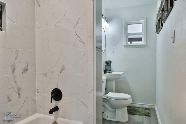 bathroom featuring tiled shower / bath combo, toilet, and wood-type flooring