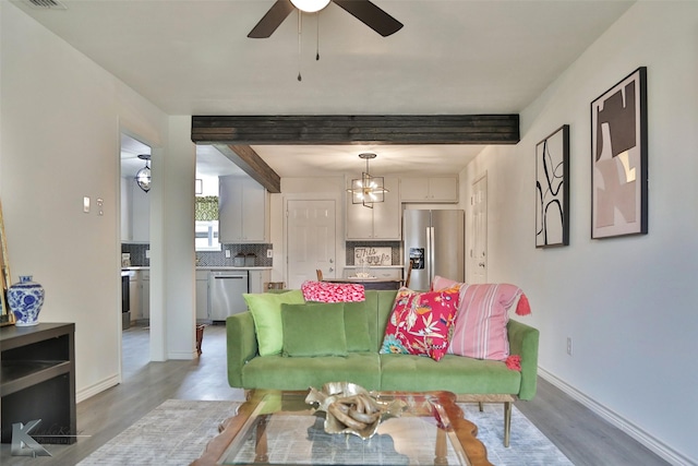 living room featuring beamed ceiling, light hardwood / wood-style floors, and ceiling fan with notable chandelier