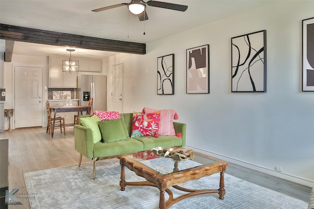 living room featuring beamed ceiling, light hardwood / wood-style floors, and ceiling fan with notable chandelier