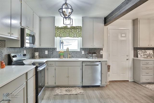 kitchen with sink, light hardwood / wood-style flooring, a notable chandelier, pendant lighting, and appliances with stainless steel finishes