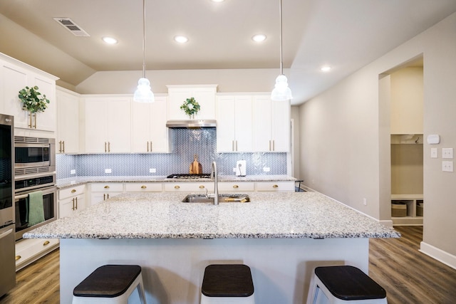 kitchen featuring a center island with sink, white cabinetry, stainless steel appliances, and hanging light fixtures