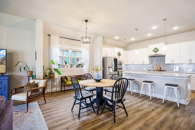 dining space with light hardwood / wood-style floors and a chandelier