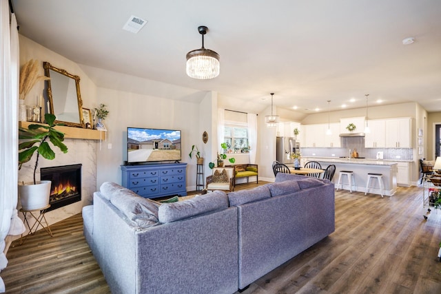 living room featuring a high end fireplace, dark hardwood / wood-style floors, and a notable chandelier