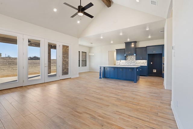 kitchen with decorative light fixtures, beamed ceiling, blue cabinetry, backsplash, and light hardwood / wood-style flooring