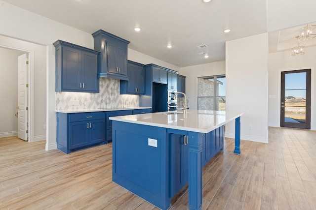 kitchen with blue cabinetry, sink, a center island with sink, a kitchen breakfast bar, and a healthy amount of sunlight