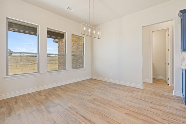 unfurnished dining area featuring a chandelier and light hardwood / wood-style flooring