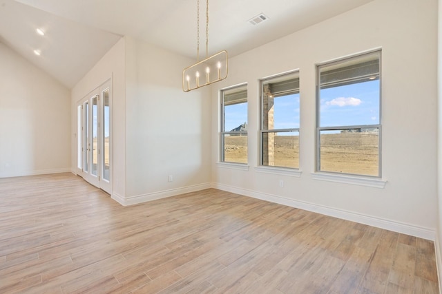 unfurnished room featuring lofted ceiling, an inviting chandelier, and light wood-type flooring