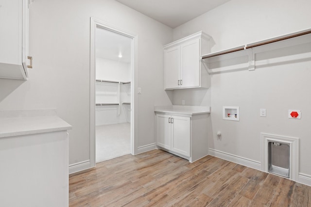 washroom featuring hookup for a washing machine, cabinets, and light hardwood / wood-style floors