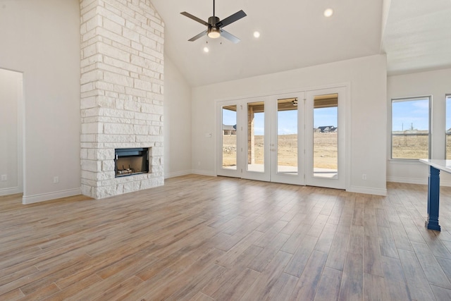 unfurnished living room featuring ceiling fan, a stone fireplace, and light hardwood / wood-style flooring