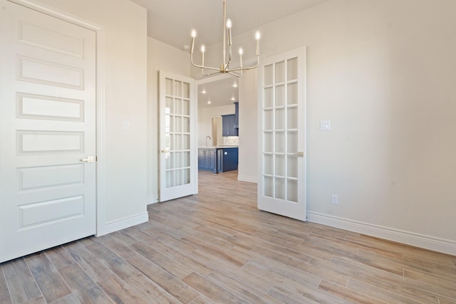 412 Collum, Azle, TX 76020 - empty room with french doors, a chandelier, baseboards, light wood-style flooring, and a sink