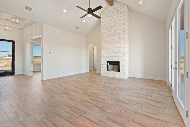 unfurnished living room featuring ceiling fan with notable chandelier, beam ceiling, high vaulted ceiling, light hardwood / wood-style floors, and a stone fireplace