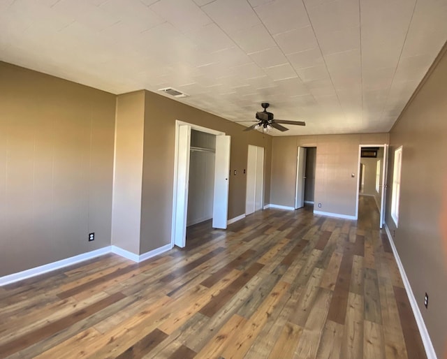 unfurnished bedroom featuring multiple closets, ceiling fan, and dark hardwood / wood-style flooring