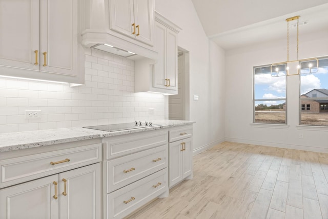 kitchen with black electric cooktop, white cabinets, pendant lighting, and light stone countertops