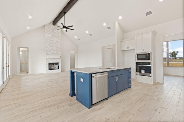 kitchen with beamed ceiling, appliances with stainless steel finishes, white cabinetry, blue cabinets, and high vaulted ceiling