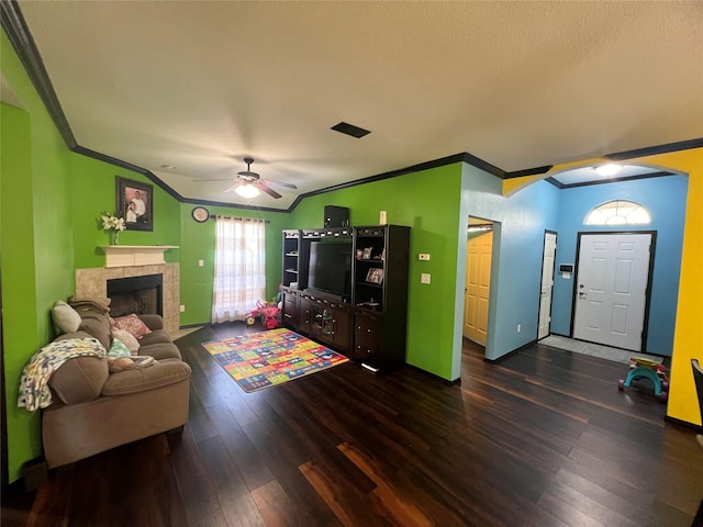 living room featuring ornamental molding, ceiling fan, dark wood-type flooring, and a tiled fireplace